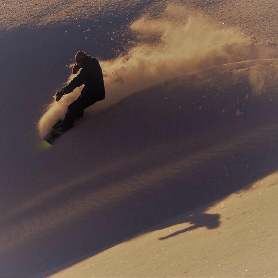 Snowskater carving big mountain powder